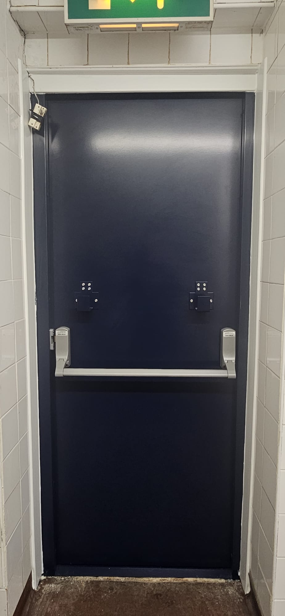 Steel fire door with push-bar exit hardware installed by Complete Door Solutions across the Central Belt